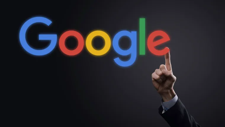 Mão de homem de terno apontando o dedo para o logotipo do Google iluminado sobre fundo escuro