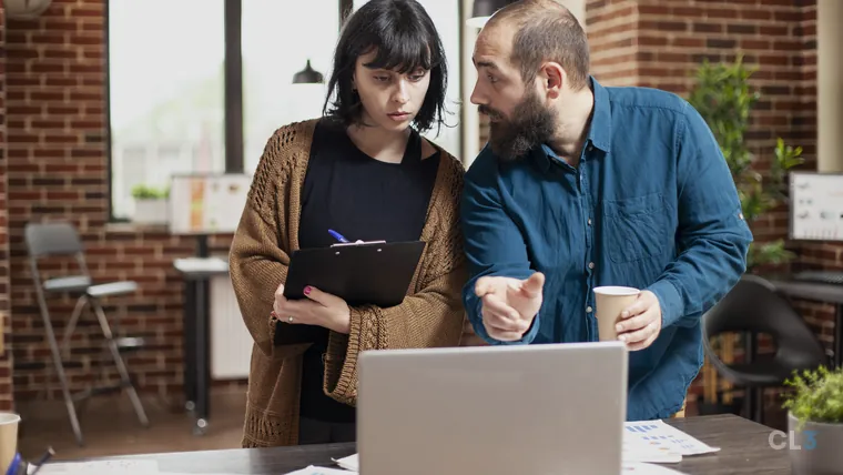 Dois profissionais conversando sobre um projeto diante do computador