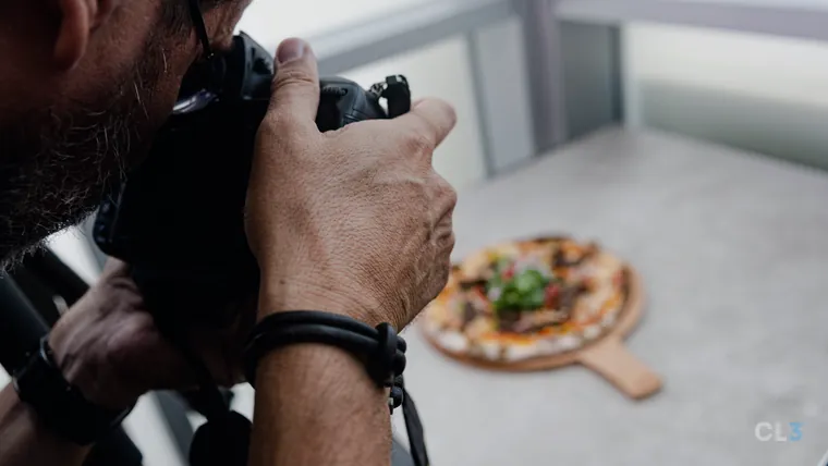 Fotógrafo fotografando uma pizza na mesa de um restaurante