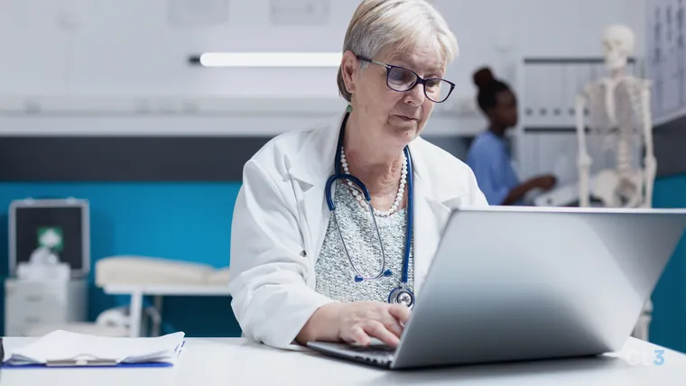 Médica com estetoscópio usando o notebook na mesa do consultório