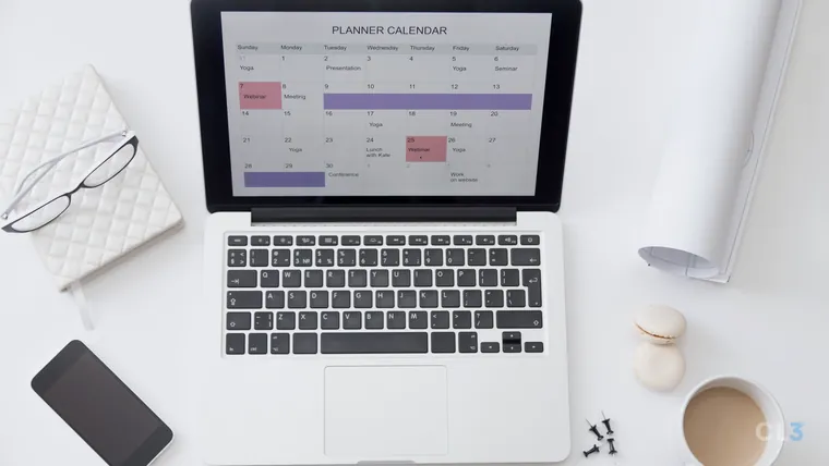 Vista de cima de uma mesa de trabalho com agenda, calendário de planejamento e notebook
