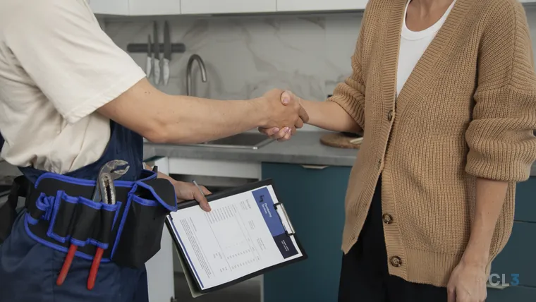 Encanador explicando o conserto a uma cliente na cozinha